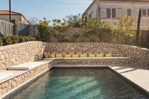 a swimming pool with benches and a stone wall at OD Luxury Villa in Pylos