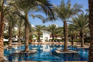 una piscina con palmeras en un complejo en Park Hyatt Dubai, en Dubái