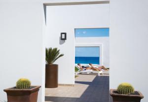 two people sitting in chairs on a patio with the ocean at Hotel Riu Palace Tres Islas in Corralejo