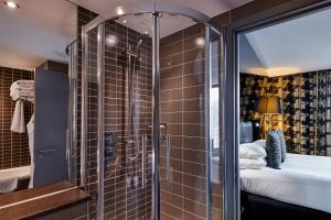 a bathroom with a glass shower and a bed at Crowne Plaza Manchester City Centre, an IHG Hotel in Manchester