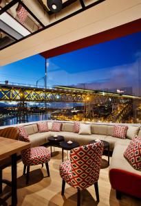 Habitación con sofá, sillas y vistas a un puente. en Vincci Ponte de Ferro, en Vila Nova de Gaia