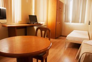 een kleine kamer met een tafel en een bureau met een laptop bij Hara Palace Hotel in Curitiba