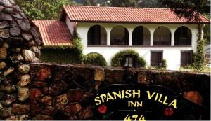 una señal frente a una pared de piedra con una casa en Spanish Villa Inn, en St. Helena