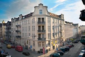 un gran edificio con coches estacionados en un estacionamiento en Apartamenty Pomarańczarnia, en Poznan