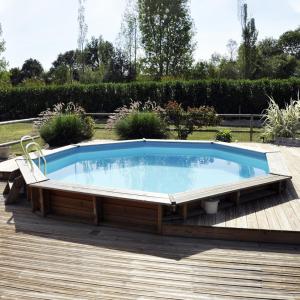 ein großer Pool auf einer Terrasse mit einem Stuhl um ihn herum in der Unterkunft Cottage du garlai in Bressuire