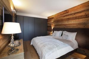 - une chambre avec un grand lit et un mur en bois dans l'établissement Petit Chalet Blanc Cervinia, à Breuil-Cervinia