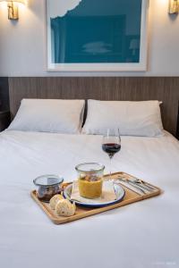 a tray of food and a glass of wine on a bed at Hotel Gascogne in Toulouse