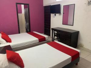 a hotel room with two beds and a desk at Hotel Aventura in Mérida