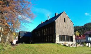 un grande fienile con un tetto nero su un prato di Krakonošova Dílna "WOODHAUS" a Špindlerův Mlýn