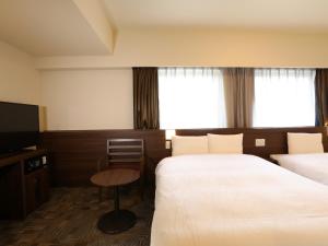 um quarto de hotel com duas camas e uma televisão em Dormy Inn Ikebukuro em Tóquio