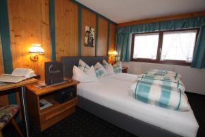 a hotel room with a large bed and a desk at Haus Alpenglühn in Längenfeld