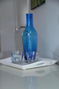 a blue vase sitting on a white plate with glasses at Cazenn Nazaré - Apartment Z in Nazaré