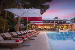 ein Pool mit Liegestühlen und einem Sonnenschirm neben einem Pool in der Unterkunft Apartments Galijot Plava Laguna in Poreč