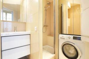 bagno con lavatrice e lavandino di Residence central marais a Parigi