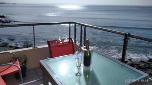 a table with a bottle of wine on a balcony with the ocean at Appartement cosy les pieds dans l’eau, vue mer exceptionnelle in Crozon