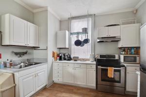 Bywater Home, Parking and Pet Friendly Retreat في نيو أورلينز: مطبخ بدولاب بيضاء ومغسلة وموقد