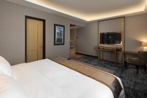 a hotel room with a large bed and a television at Sutasoma Hotel in Jakarta