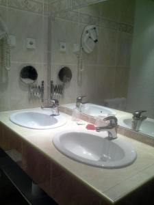 Baño con 2 lavabos y espejo en Hotel Panda, en Pas de la Casa