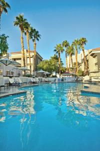 una gran piscina con palmeras en el fondo en Desert Rose Resort, en Las Vegas