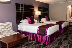 a hotel room with two beds and a chair at Gateway Inn and Suites in Salida