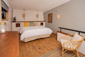 1 dormitorio con 1 cama y 1 silla en Cala Melí, en Puerto Varas