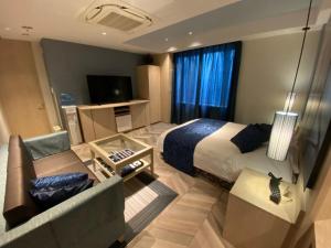 een hotelkamer met een bed, een bank en een televisie bij ルトゥール姫路 Retur HIMEJI 男塾ホテルグループ in Himeji