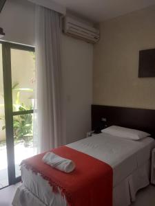 a bedroom with a bed with a red blanket and a window at Pousada Aquarela Do Brasil in Maceió