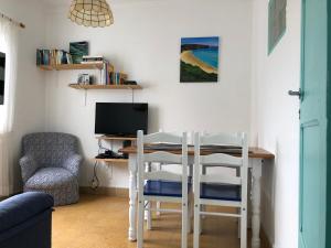 een tafel met 2 stoelen en een bureau met een computer bij Casa do Viajante - Family in Zambujeira do Mar