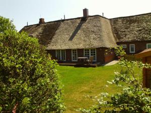 an old house with a thatched roof and a yard at Ferienwohnung Abelke in Utersum