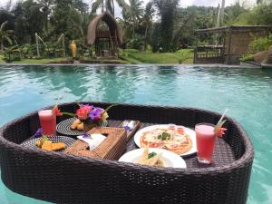 una mesa con comida y bebida junto a una piscina en Pondok Sebatu Eco Lodge, en Tegalalang