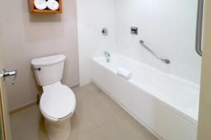 La salle de bains blanche est pourvue de toilettes et d'une baignoire. dans l'établissement Staybridge Suites Guadalajara Expo, an IHG Hotel, à Guadalajara