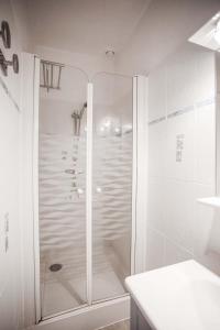 Baño blanco con ducha con puerta de cristal en Résidence Le Roc Fleuri, en Saint-Malo