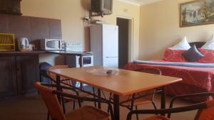 una pequeña cocina con mesa y nevera en Amberlight Self Catering Accommodation, en Krugersdorp