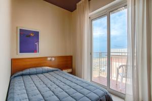 a bedroom with a bed and a large window at Hotel Ancora in Lido di Jesolo