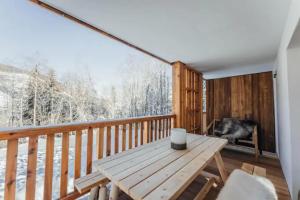 uma varanda em madeira com uma mesa e uma grande janela em Le Refuge des Anges em Megève