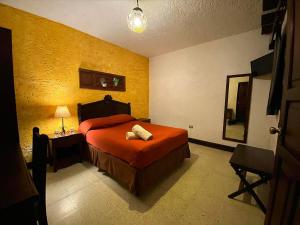 a bedroom with a bed and a table and a mirror at Hotel Posada San Pedro in Antigua Guatemala