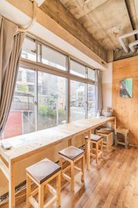 熱海市にあるArtBar & GuestHouse ennovaの大きな窓のある部屋(大きな木製テーブル付)