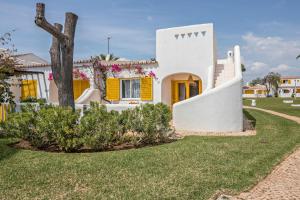 una casa blanca con puertas amarillas y un árbol en Casa O12, en Vilamoura