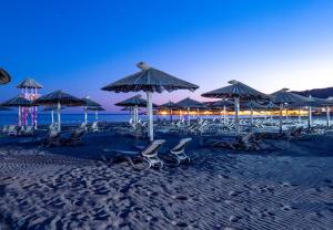 eine Gruppe von Stühlen und Sonnenschirmen am Strand in der Unterkunft Beach Walk Apartments in Ulcinj