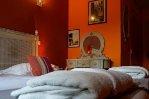 a bedroom with orange walls and a bed and a mirror at Auberge du Manet in Montigny-le-Bretonneux