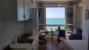 - une cuisine avec une fenêtre offrant une vue sur l'océan dans l'établissement Arteg Apartments - Full Sea View, à Durrës