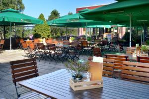 un patio con mesas, sillas y sombrillas verdes en Hotel Kaiseralm, en Bischofsgrün