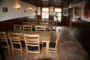 een eetkamer met een grote houten tafel en stoelen bij Hotel de Harmonie in Sexbierum