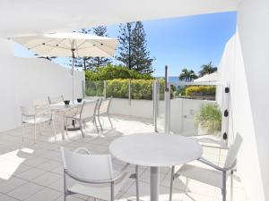 a patio with tables and chairs and an umbrella at Sirocco 202 in Mooloolaba