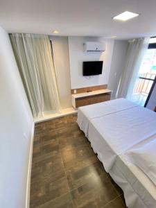 a bedroom with a white bed and a television at Swell Praia Hotel in Natal