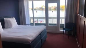 een hotelkamer met een bed en uitzicht op het water bij Boutique Hotel Zaan in Zaandijk