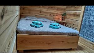 a wooden bed with two blue pillows on it at Lāču namiņš/Bear house in Liepāja