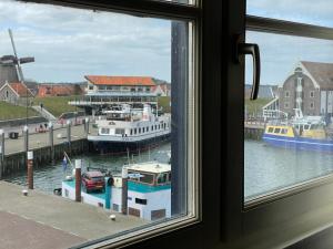 okno z widokiem na łodzie w porcie w obiekcie Havenhotel At Sea Texel w mieście Oudeschild