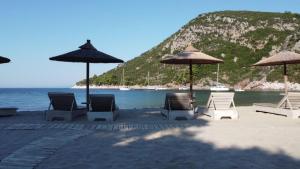 un gruppo di sedie e ombrelloni in spiaggia di Limnonari Beach Rooms a Skopelos Town