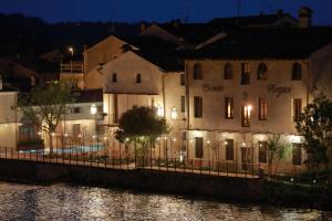 een groep gebouwen naast een rivier 's nachts bij Corte Regia Relais & Spa in Valeggio sul Mincio